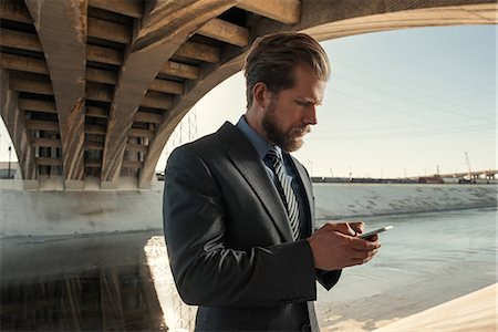 Businessman texting, Los Angeles river, California, USA Stock Photo - Premium Royalty-Free, Code: 614-08684928