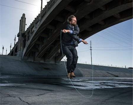 Businessman skipping, Los Angeles river, California, USA Stock Photo - Premium Royalty-Free, Code: 614-08684923