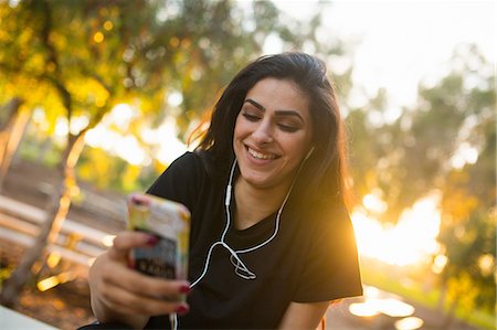 Young woman, outdoors, wearing earphones, holding smartphone Fotografie stock - Premium Royalty-Free, Codice: 614-08685141