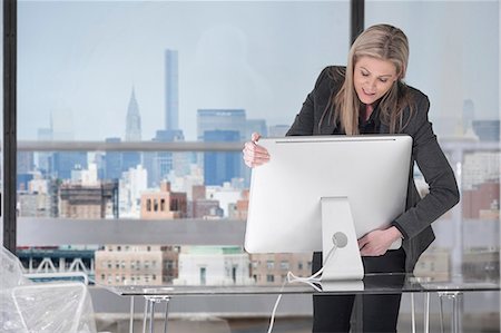 Businesswoman setting up computer in office Stock Photo - Premium Royalty-Free, Code: 614-08685283