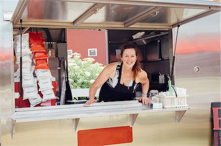 Portrait of woman leaning forward at hatch of food stall trailer Foto de stock - Sin royalties Premium, Código: 614-08726394