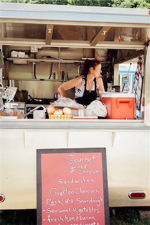 Woman looking out from food stall trailer Fotografie stock - Premium Royalty-Free, Codice: 614-08726395