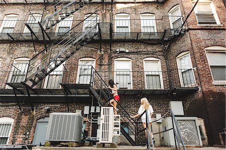 escalera de incendios - Women climbing fire escape ladder of apartment building, Boston, MA, USA Foto de stock - Sin royalties Premium, Código: 614-08726476
