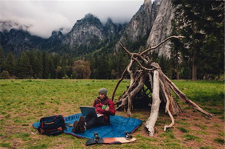 Hiker sitting by den using laptop, Yosemite, California, USA Stock Photo - Premium Royalty-Free, Code: 614-08726644