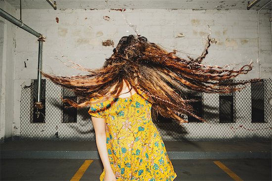 Front view of young woman shaking her long wavy hair in indoor carpark Stock Photo - Premium Royalty-Free, Image code: 614-08726729