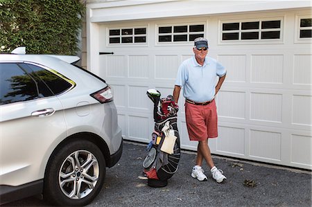 Portrait of senior male golfer standing next to garage door with golf bag Foto de stock - Sin royalties Premium, Código: 614-08720581