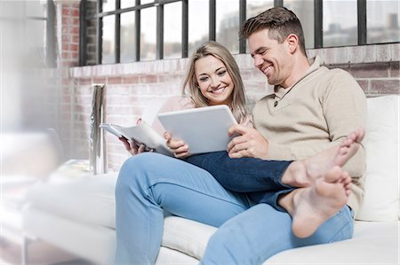 photography lounge sofa - Couple at home, relaxing on sofa, looking at digital tablet Stock Photo - Premium Royalty-Free, Code: 614-08720612