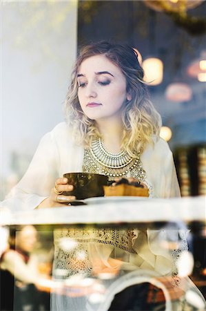 View through coffee shop window of woman with coffee Stock Photo - Premium Royalty-Free, Code: 614-08720637