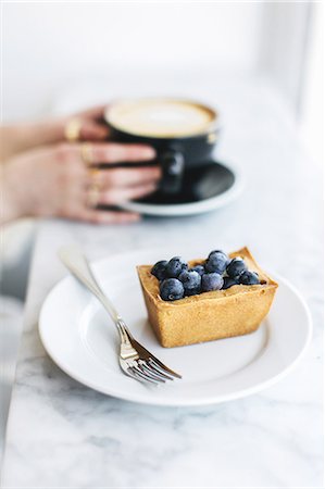 self indulgence - Fruit tart and woman's hands holding frothy coffee Stock Photo - Premium Royalty-Free, Code: 614-08720632