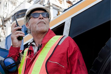 sunglasses wearing men - Engineer using walkie talkie on oil rig Stock Photo - Premium Royalty-Free, Code: 614-08720663