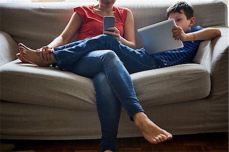 Mother and son relaxing on sofa using digital tablet and smartphone Photographie de stock - Premium Libres de Droits, Code: 614-08721050