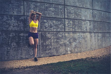 simsearch:614-08768461,k - Young woman stretching outdoors, leaning against wall Foto de stock - Sin royalties Premium, Código: 614-08768484