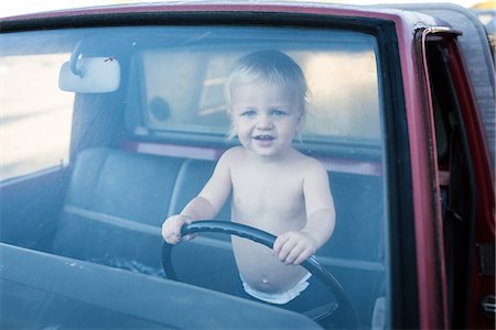 Portrait of male toddler standing in truck holding steering wheel Stock Photo - Premium Royalty-Free, Code: 614-08768498