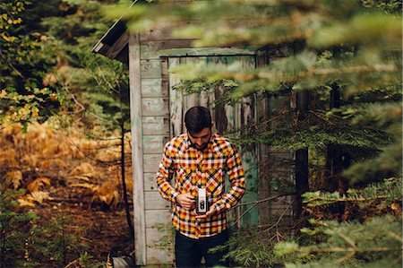simsearch:614-06895809,k - Young man standing near cabin in forest, taking photograph with camera, near Shaver Lake, California, USA Photographie de stock - Premium Libres de Droits, Code: 614-08826860