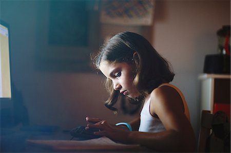 Girl using computer in dimly-lit room Fotografie stock - Premium Royalty-Free, Codice: 614-08826990