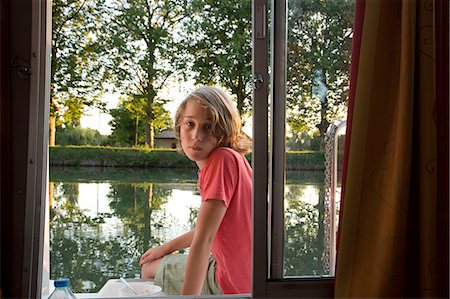 Boy sitting on side of barge, looking through window Stock Photo - Premium Royalty-Free, Code: 614-08827038