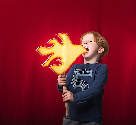 representation - Boy holding cardboard cutout of flames pretending to breathe fire Photographie de stock - Premium Libres de Droits, Code: 614-08827127