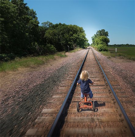 Rear view of boy riding tricycle on railway track Stock Photo - Premium Royalty-Free, Code: 614-08827154