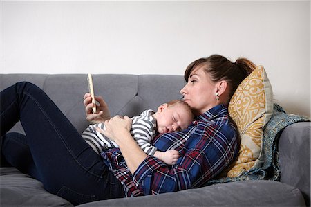 simsearch:6102-08558784,k - Mother with baby boy lying on sofa looking at smartphone Foto de stock - Sin royalties Premium, Código: 614-08827186