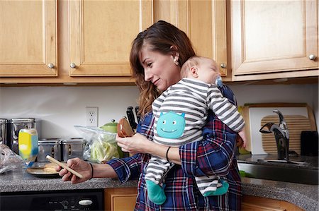 Mother holding sleeping baby boy and looking at smartphone Stock Photo - Premium Royalty-Free, Code: 614-08827183