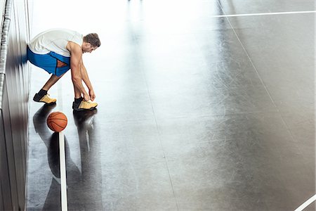simsearch:614-08827243,k - Male basketball player tying trainer laces on basketball court Stock Photo - Premium Royalty-Free, Code: 614-08827239