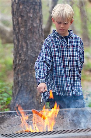 sedona - Boy barbecuing sausage on flaming grill in forest, Sedona, Arizona, USA Fotografie stock - Premium Royalty-Free, Codice: 614-08821099