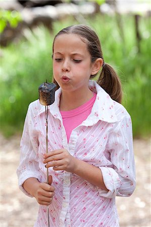 sedona - Girl blowing toasted marshmallow in forest, Sedona, Arizona, USA Fotografie stock - Premium Royalty-Free, Codice: 614-08821100