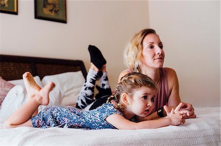 Woman lying on bed with toddler daughter watching TV Stock Photo - Premium Royalty-Free, Code: 614-08821166