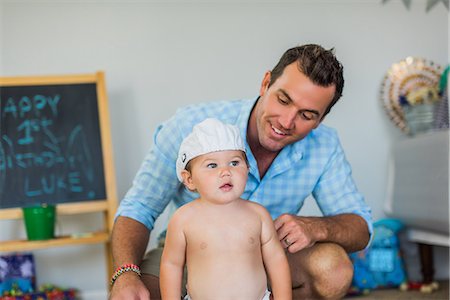 Father smiling at toddler wearing funny hat Photographie de stock - Premium Libres de Droits, Code: 614-08821216