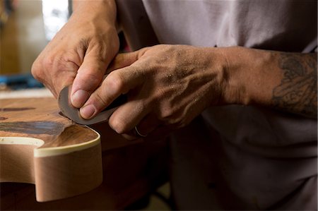 Guitar maker in workshop sanding guitar Photographie de stock - Premium Libres de Droits, Code: 614-08821275