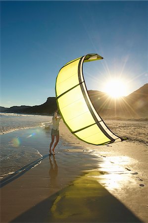 Woman holding kitesurfing sail on beach. Stock Photo - Premium Royalty-Free, Code: 614-08865487