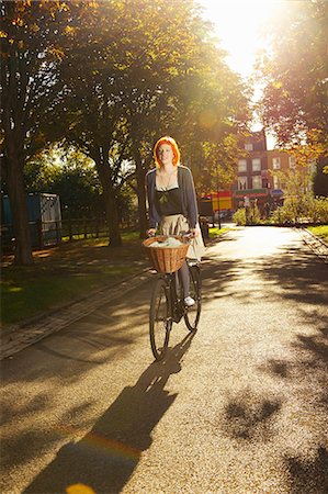 riding bike with basket - Young redhead woman cycling in park Stock Photo - Premium Royalty-Free, Code: 614-08865810