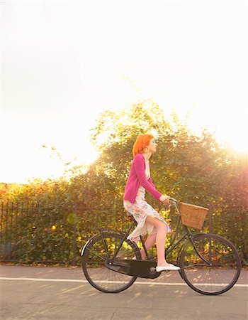 riding bike with basket - Young redhead woman cycling in park Stock Photo - Premium Royalty-Free, Code: 614-08865811