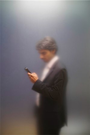 Man with phone behind frosted screen Stock Photo - Premium Royalty-Free, Code: 614-08865822