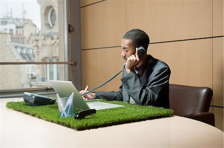 Man phoning at grass-covered desk Stock Photo - Premium Royalty-Free, Code: 614-08866447