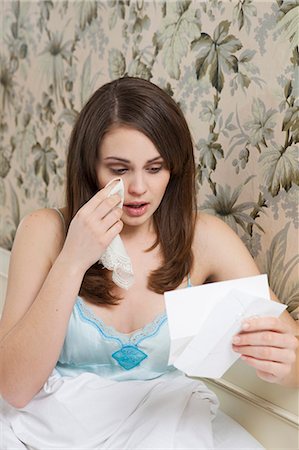 person wiping tears - woman in bed,reading letter,crying Stock Photo - Premium Royalty-Free, Code: 614-08866598