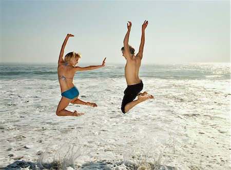 Couple leaping into waves on beach Stock Photo - Premium Royalty-Free, Code: 614-08866621