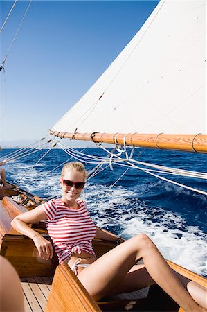 rich women sunbathing - woman smiling sitting on deck Stock Photo - Premium Royalty-Free, Code: 614-08866819