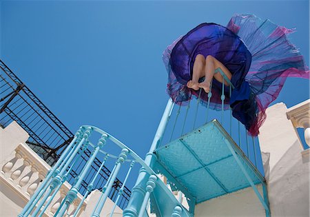 Woman sitting on staircase railing Stock Photo - Premium Royalty-Free, Code: 614-08867633