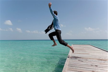 excited jumping suit - Businessman jumping from jetty into sea Stock Photo - Premium Royalty-Free, Code: 614-08867716