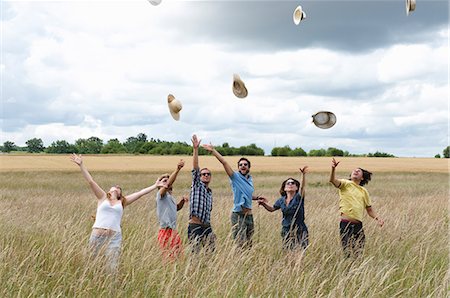 People in field tossing hats in air Fotografie stock - Premium Royalty-Free, Codice: 614-08867767