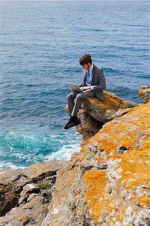 Businessman using laptop on cliff Stock Photo - Premium Royalty-Free, Code: 614-08867816