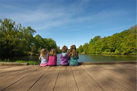 Children sitting on wooden dock in lake Stock Photo - Premium Royalty-Free, Code: 614-08867875