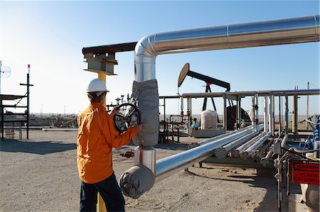 Worker adjusting pipes at oil field Stock Photo - Premium Royalty-Free, Code: 614-08867894