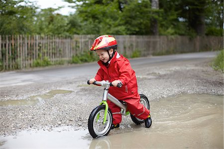 Smiling boy riding bicycle in puddles Foto de stock - Sin royalties Premium, Código: 614-08867918