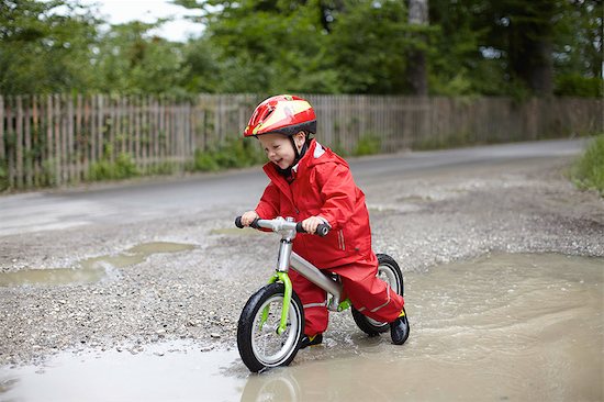 Smiling boy riding bicycle in puddles Foto de stock - Sin royalties Premium, Código de la imagen: 614-08867918