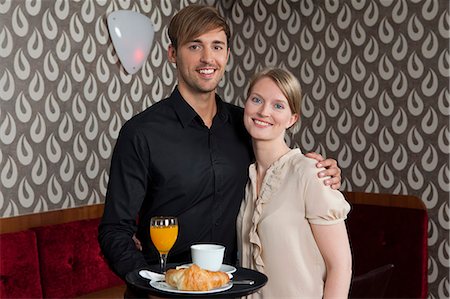 Waiter with tray of food hugging woman Stock Photo - Premium Royalty-Free, Code: 614-08868084