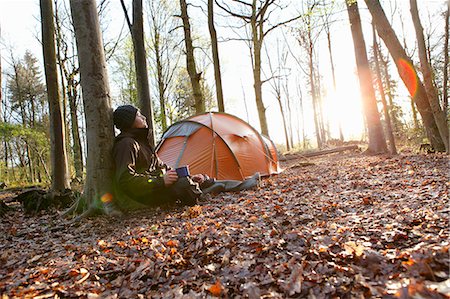 Man drinking coffee by tent in forest Stock Photo - Premium Royalty-Free, Code: 614-08869939