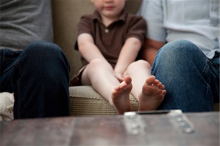 feet couch - Boy sitting on sofa with grown-ups Stock Photo - Premium Royalty-Free, Code: 614-08874020