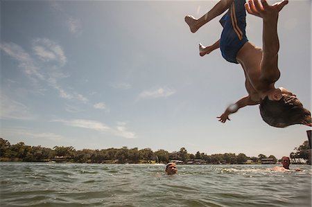 Boy doing backflip into water Fotografie stock - Premium Royalty-Free, Codice: 614-08874321